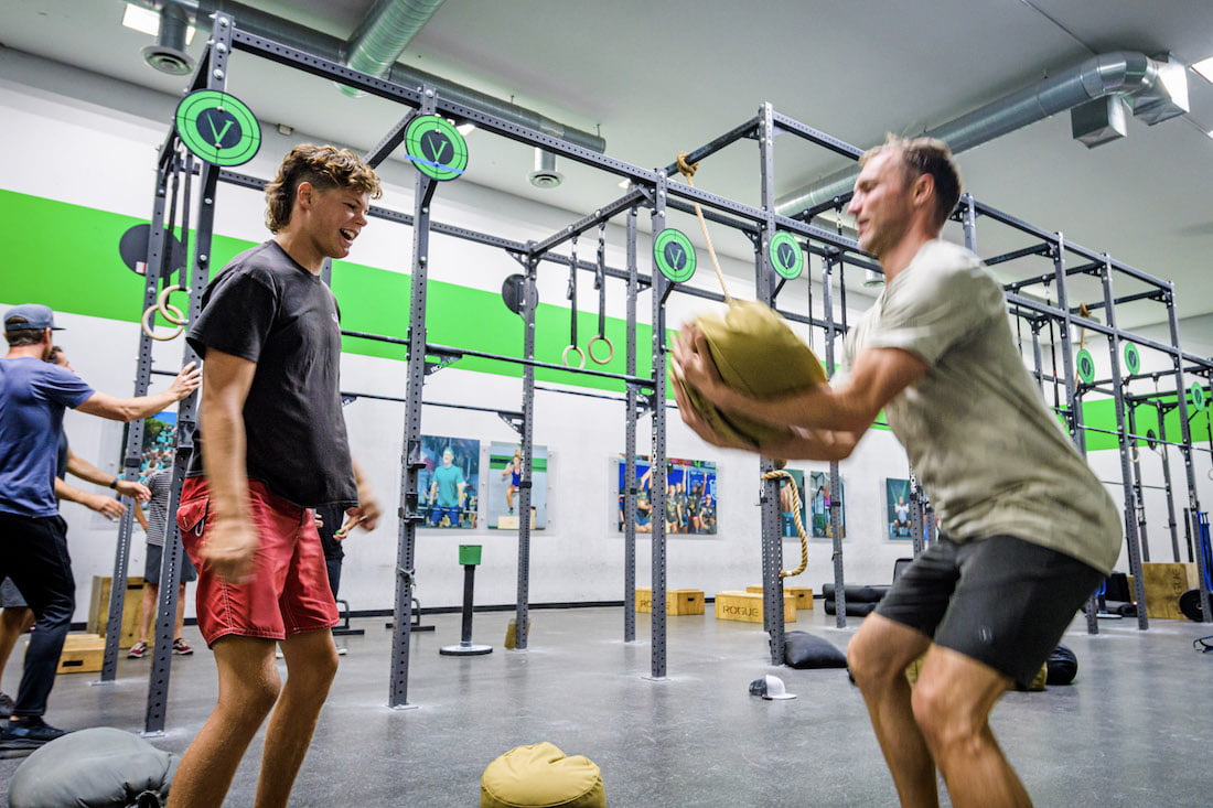 Forge attendee and Adam Dirks throw sandbags back and forth to one another for a partner exercise at the crossfit gym.