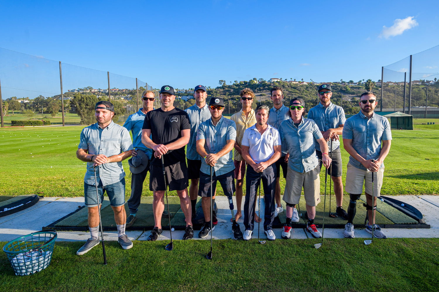 Group photo of the Forge men at the golf driving range with their golf clubs.