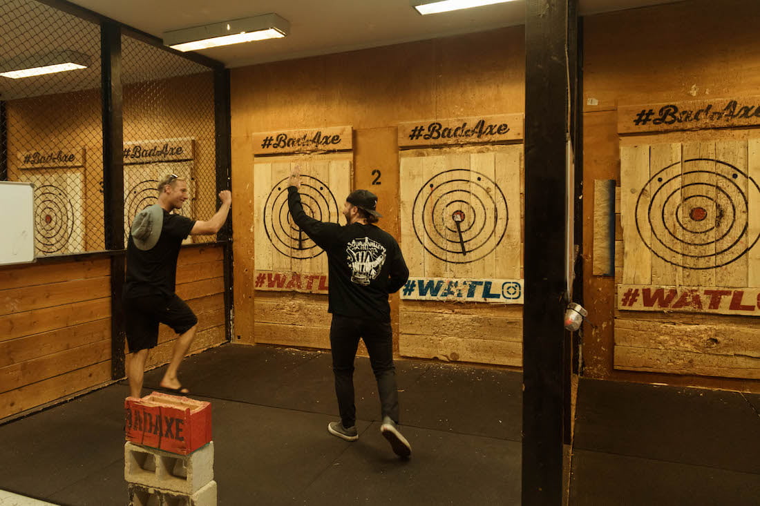 Two Forge men go to give each other high fives after getting bullseyes in axe throwing.