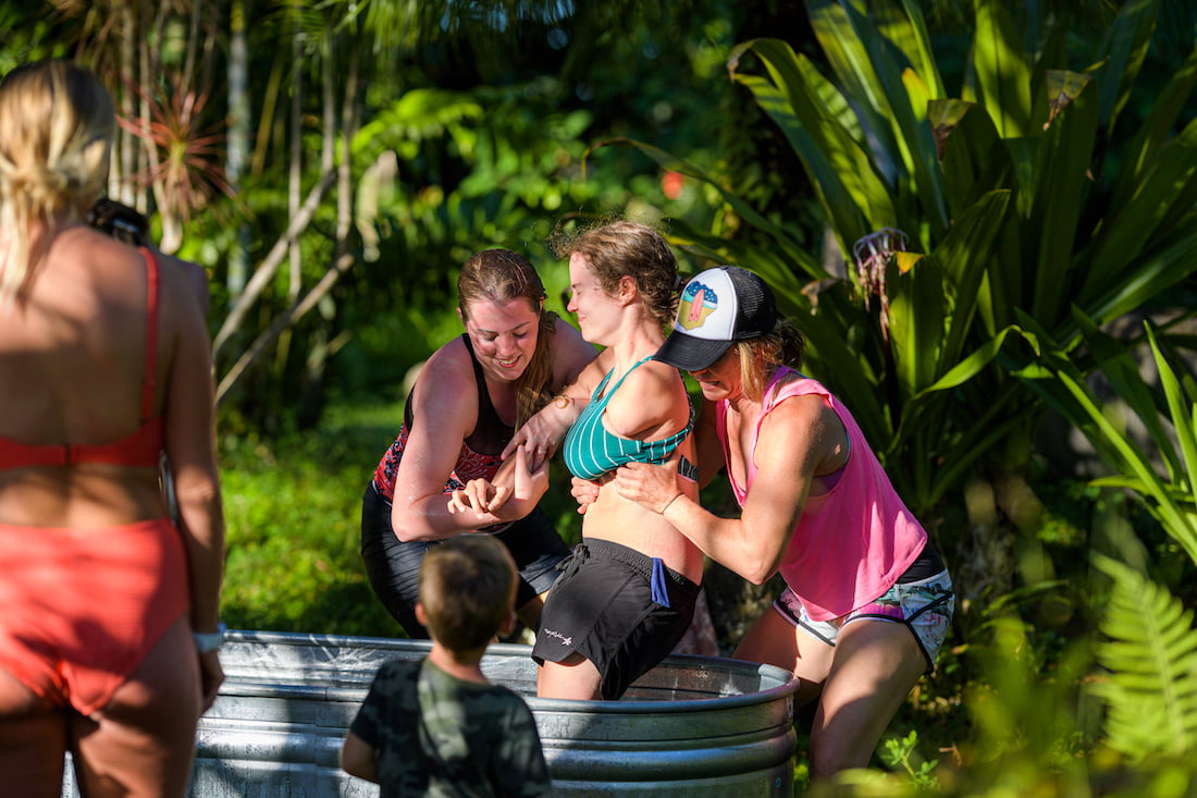 A retreat attendee and volunteer assist another amputee by lifting her into the cold plunge tub for her to try completing this cold challenge that has many physical health benefits.