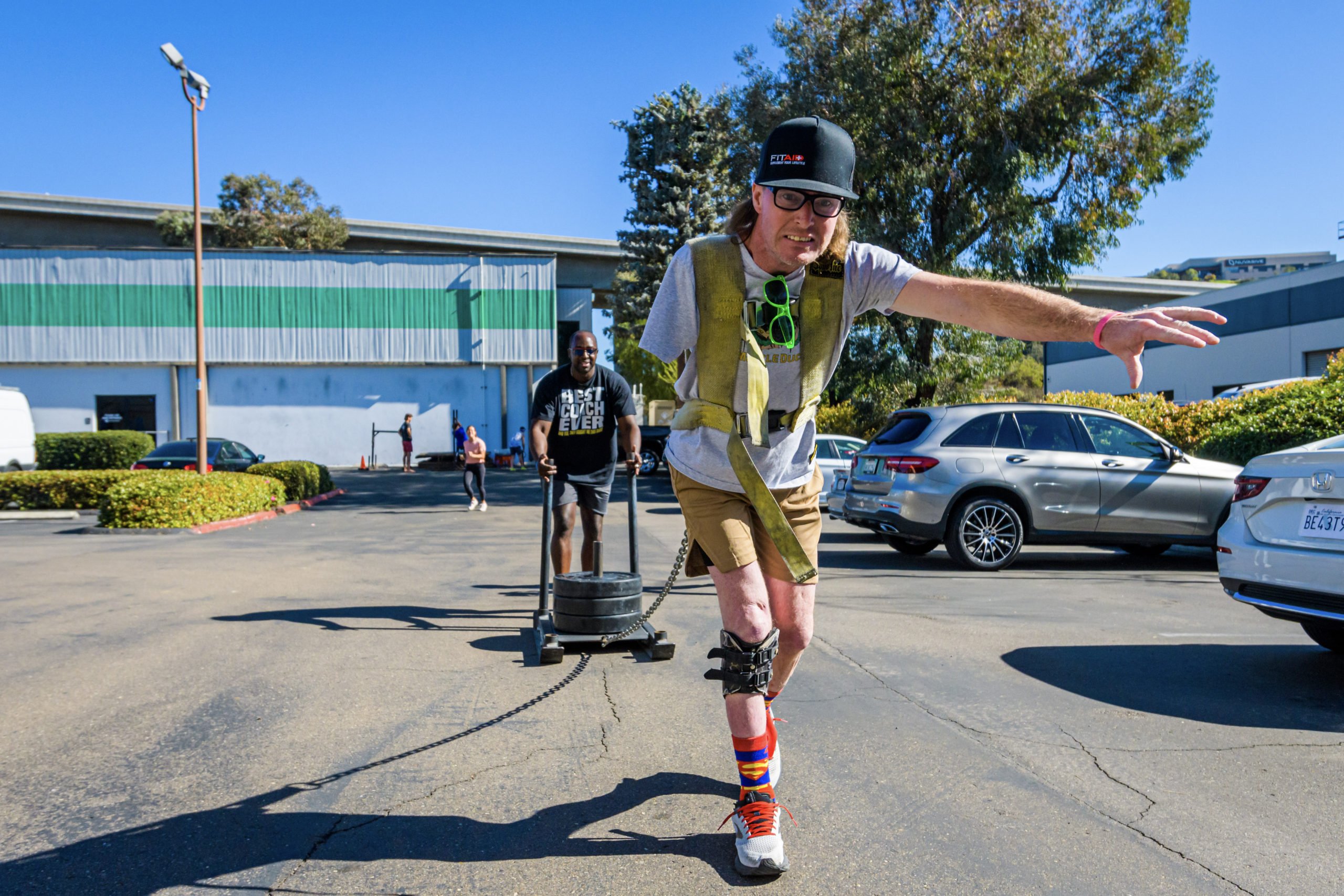 Forge attendee Shane, with a determined face, pulls a weighted sled as arm amputee through the parking lot to complete the workout.