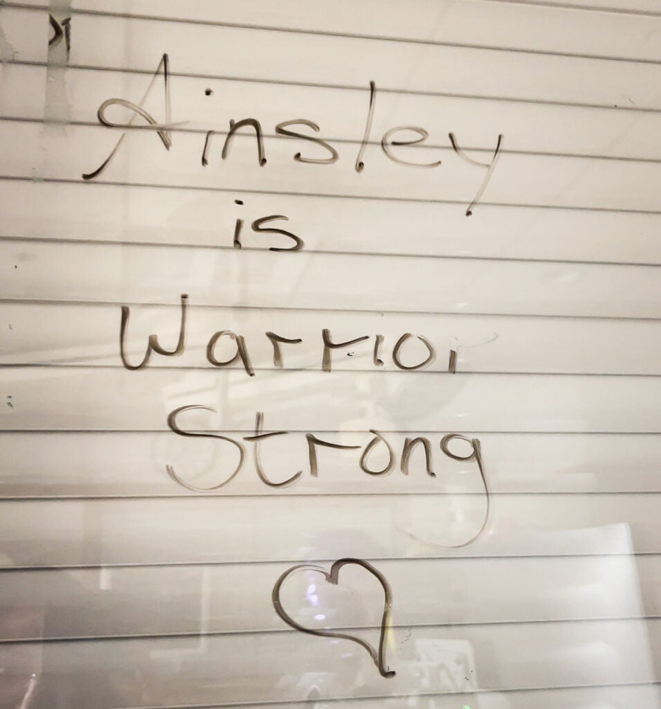 A declaration and prayer "Ainsley is warrior strong" written on a white board in a prayer closet.