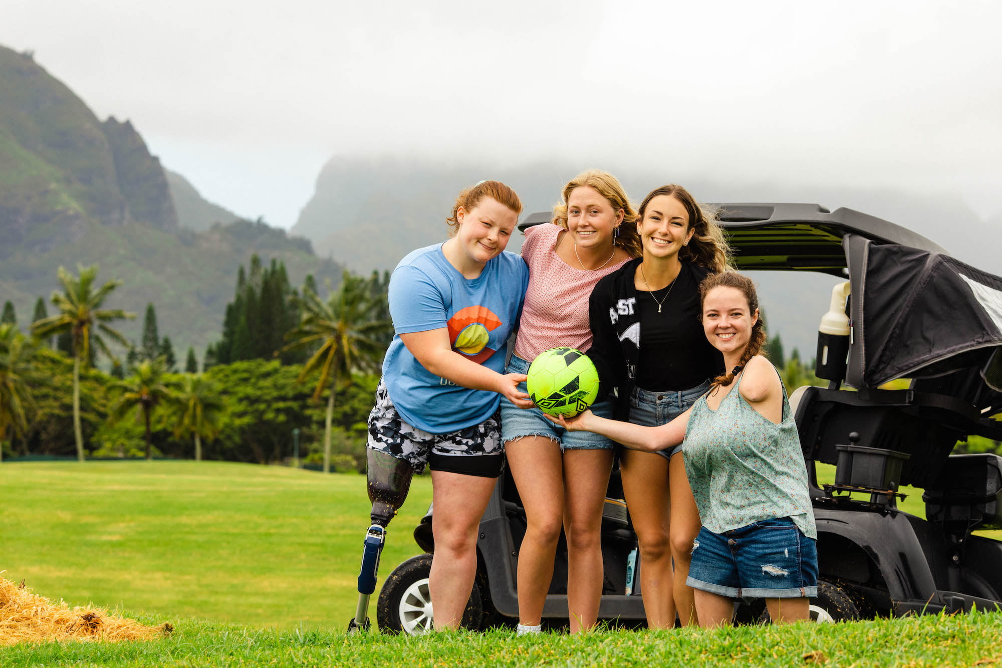 Group photo of attendees with a soccer ball and golf cart