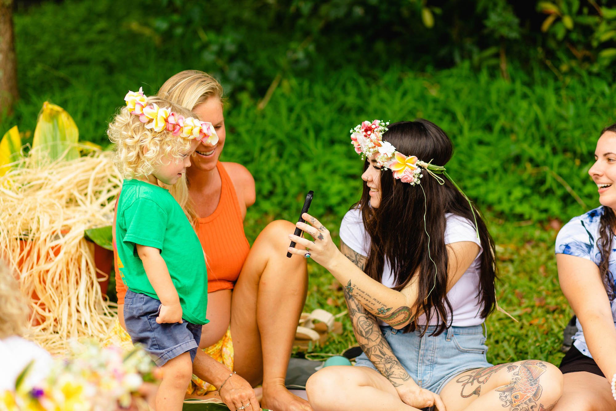 Retreat attendee showing Bethany Hamilton and her son Micah something on her phone while wearing her lei po'o